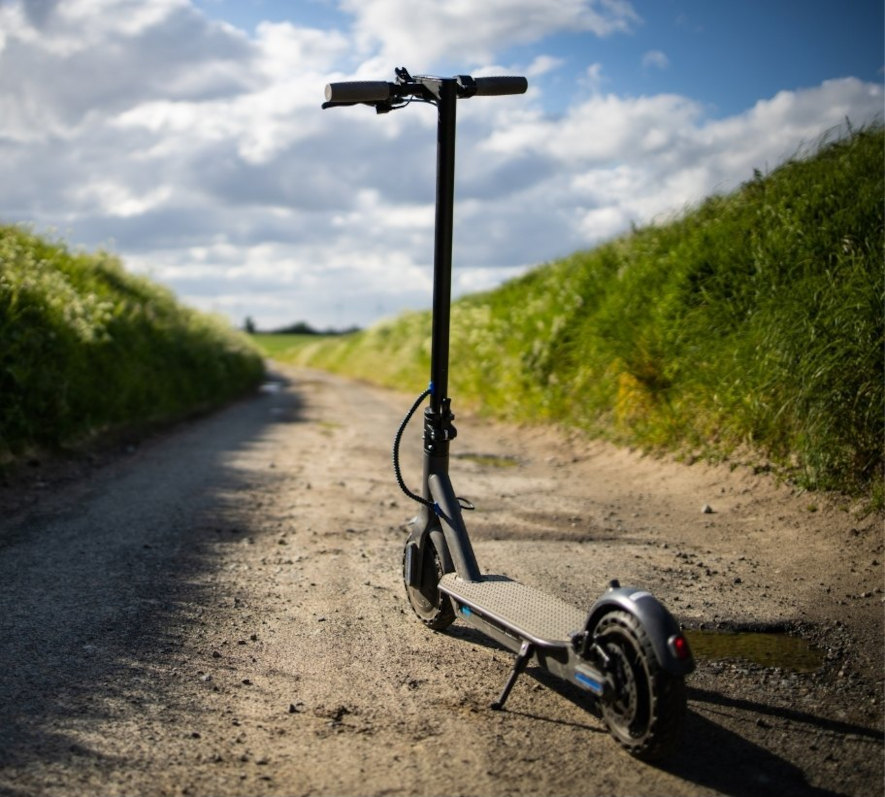 Elsparkcykel parkerad på grusväg en solig sommardag